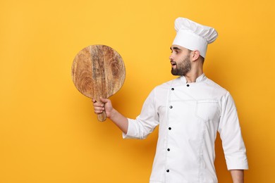 Professional chef with serving board on yellow background