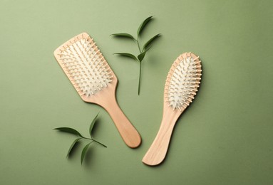 Photo of Bamboo hairbrushes on green background, flat lay. Conscious consumption