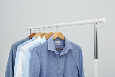 Photo of Rack with stylish men's clothes on light background