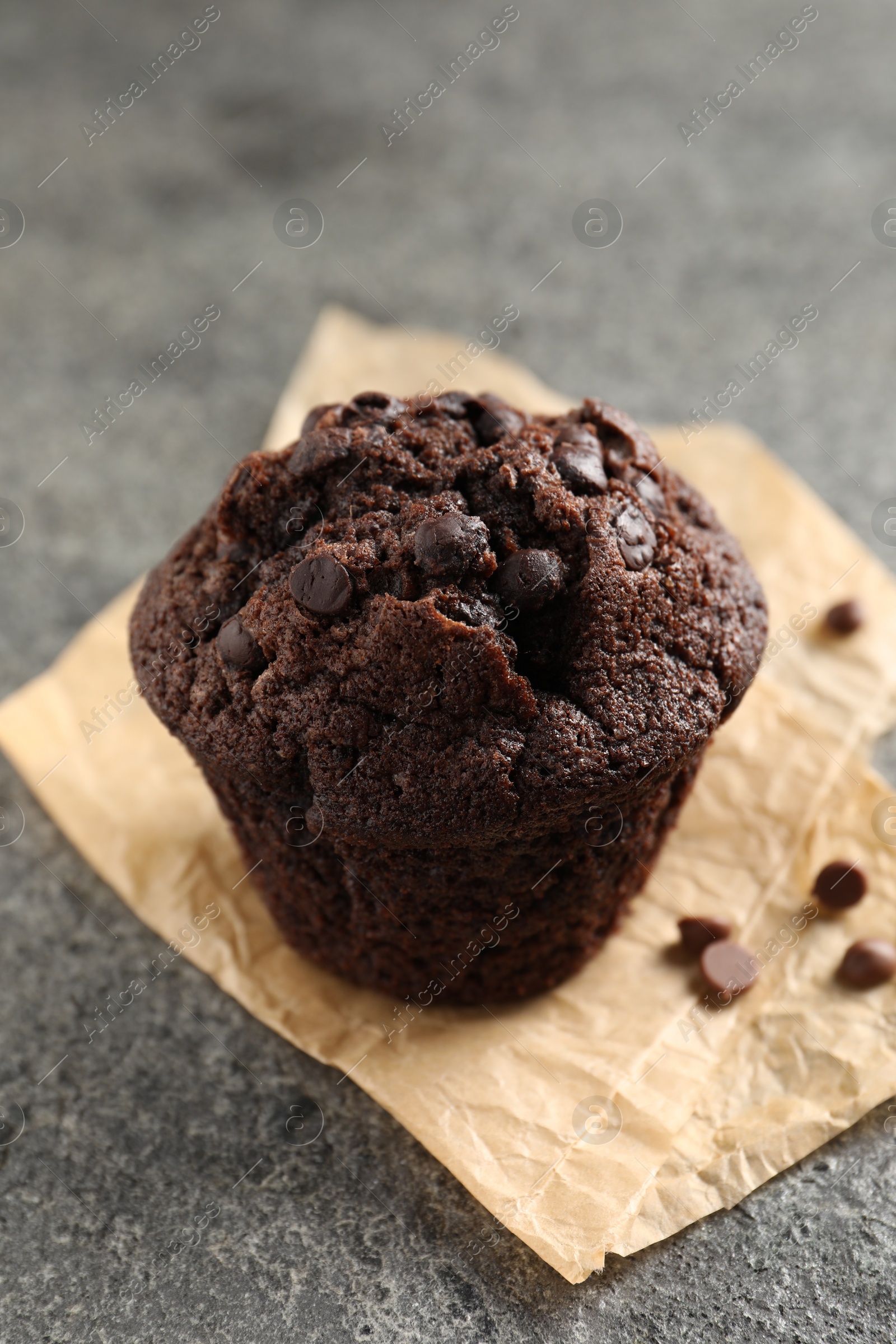 Photo of Delicious chocolate muffin on grey textured table, closeup