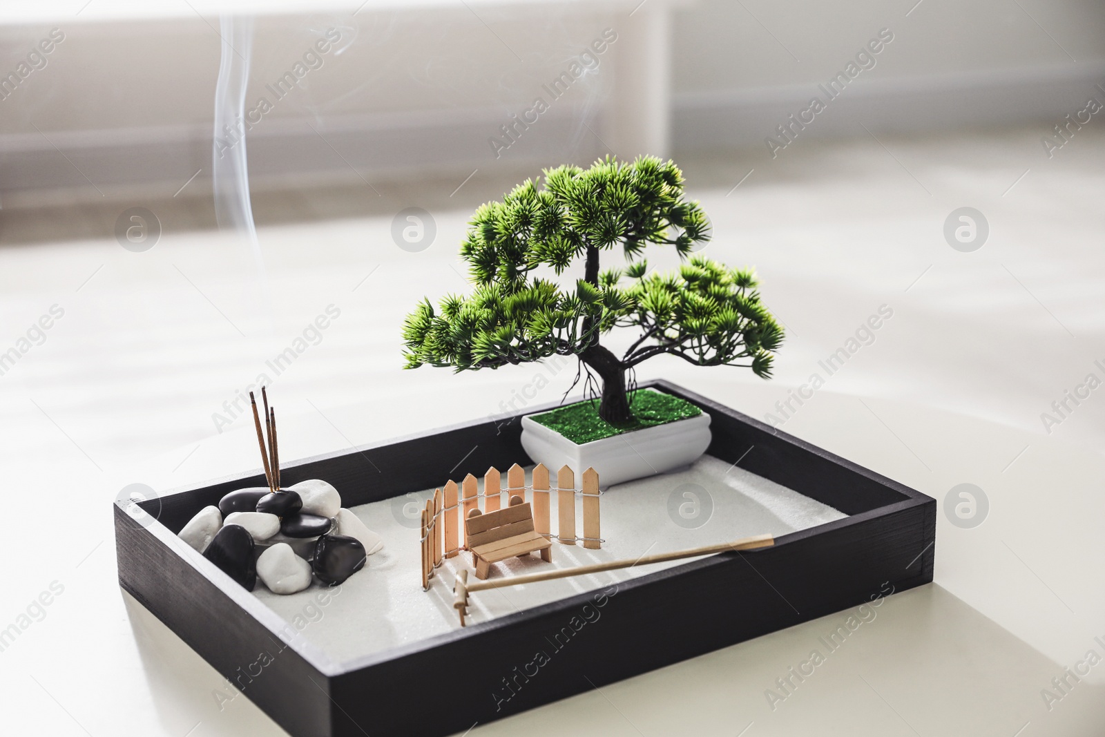 Photo of Beautiful miniature zen garden with incense sticks on table indoors