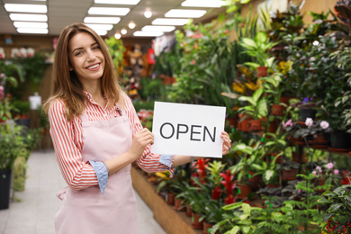 Young business owner holding OPEN sign in flower shop