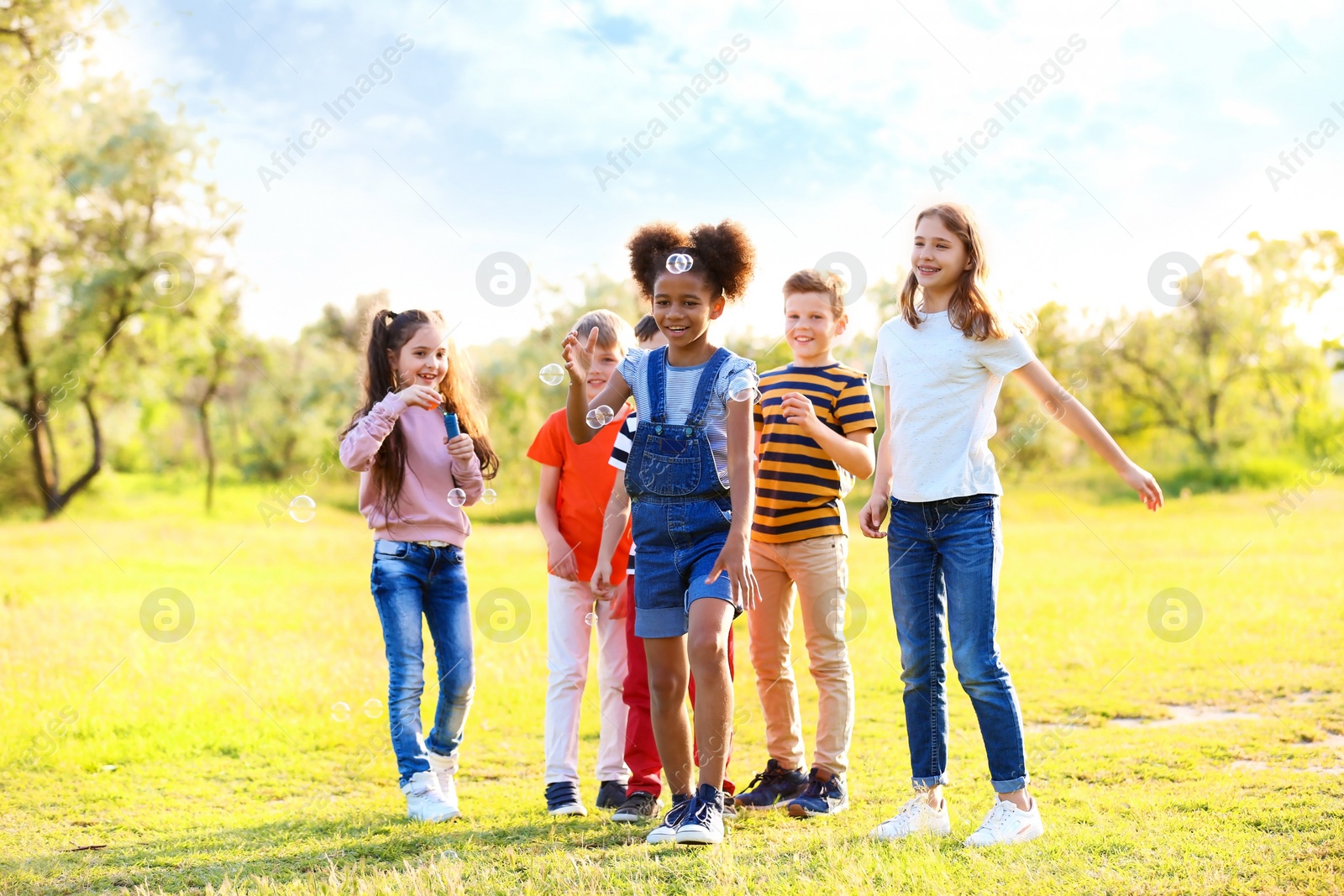 Photo of Cute little children playing with soap bubbles outdoors on sunny day