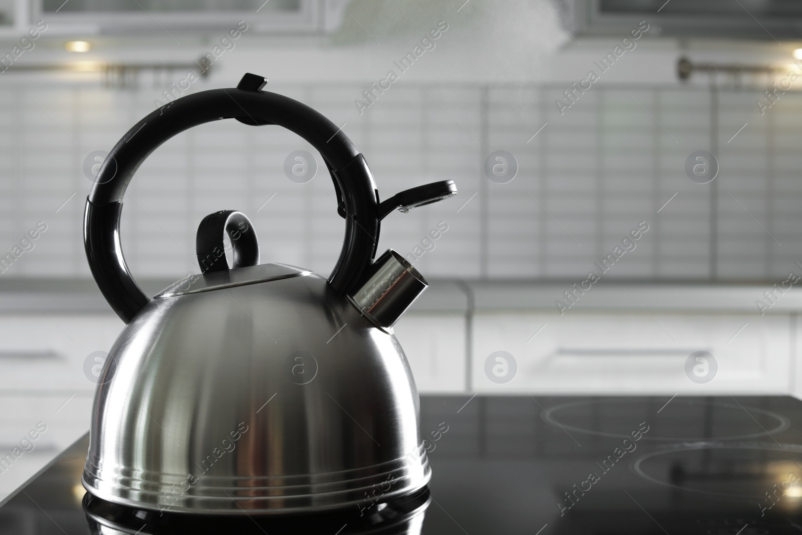 Photo of Modern kettle with whistle on stove in kitchen, space for text