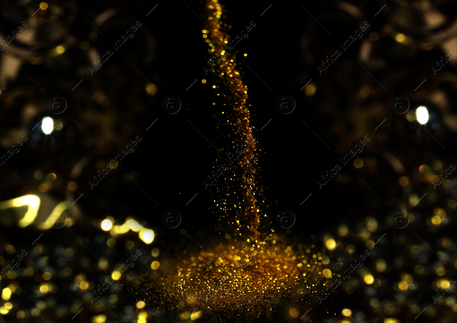 Photo of Sprinkling gold glitter on black background, bokeh effect