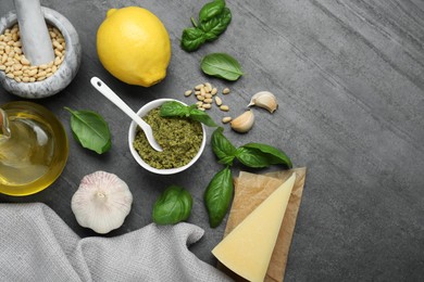 Photo of Delicious pesto sauce and ingredients on grey table, flat lay. Space for text