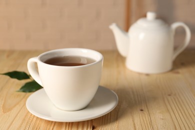 Photo of Tasty tea in cup on light wooden table, closeup. Space for text