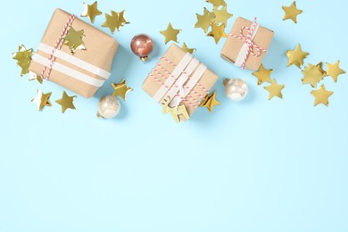 Gift boxes, Christmas balls and golden confetti on light blue background, flat lay. Space for text