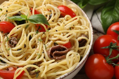 Delicious pasta with anchovies, tomatoes and spices in bowl, closeup