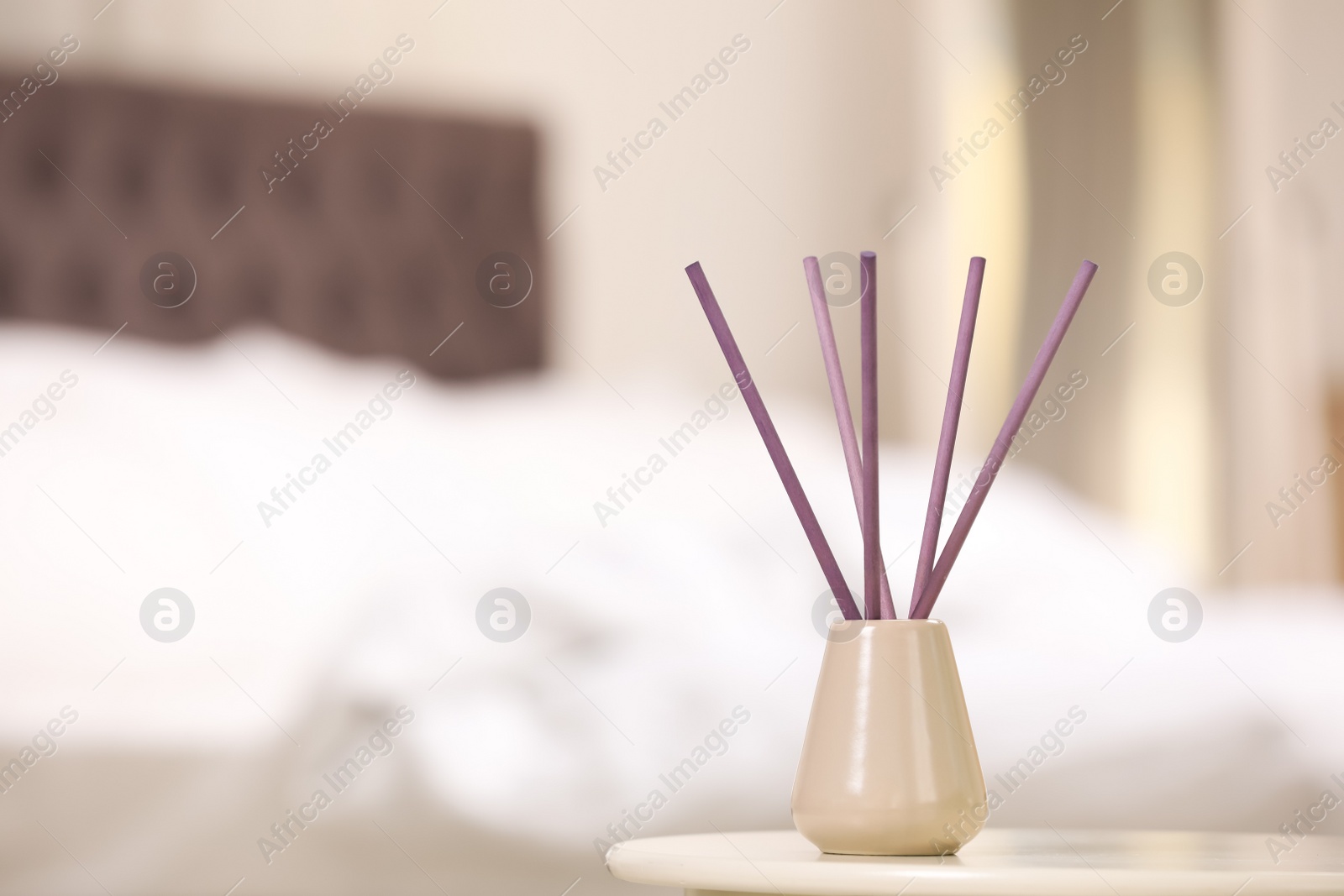 Photo of Reed air freshener with essential oil on table indoors. Space for text