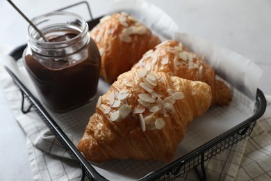 Photo of Delicious croissants with almond flakes and chocolate paste on light grey table, closeup