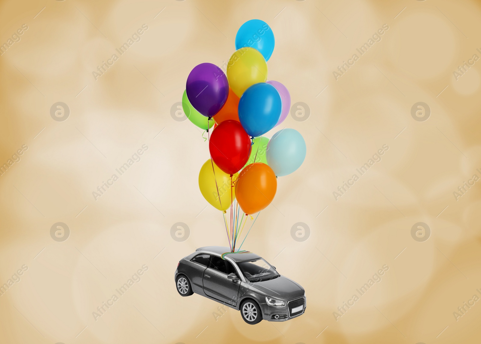 Image of Many balloons tied to toy car flying on golden background