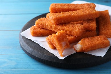 Photo of Fresh breaded fish fingers served on light blue wooden table, space for text