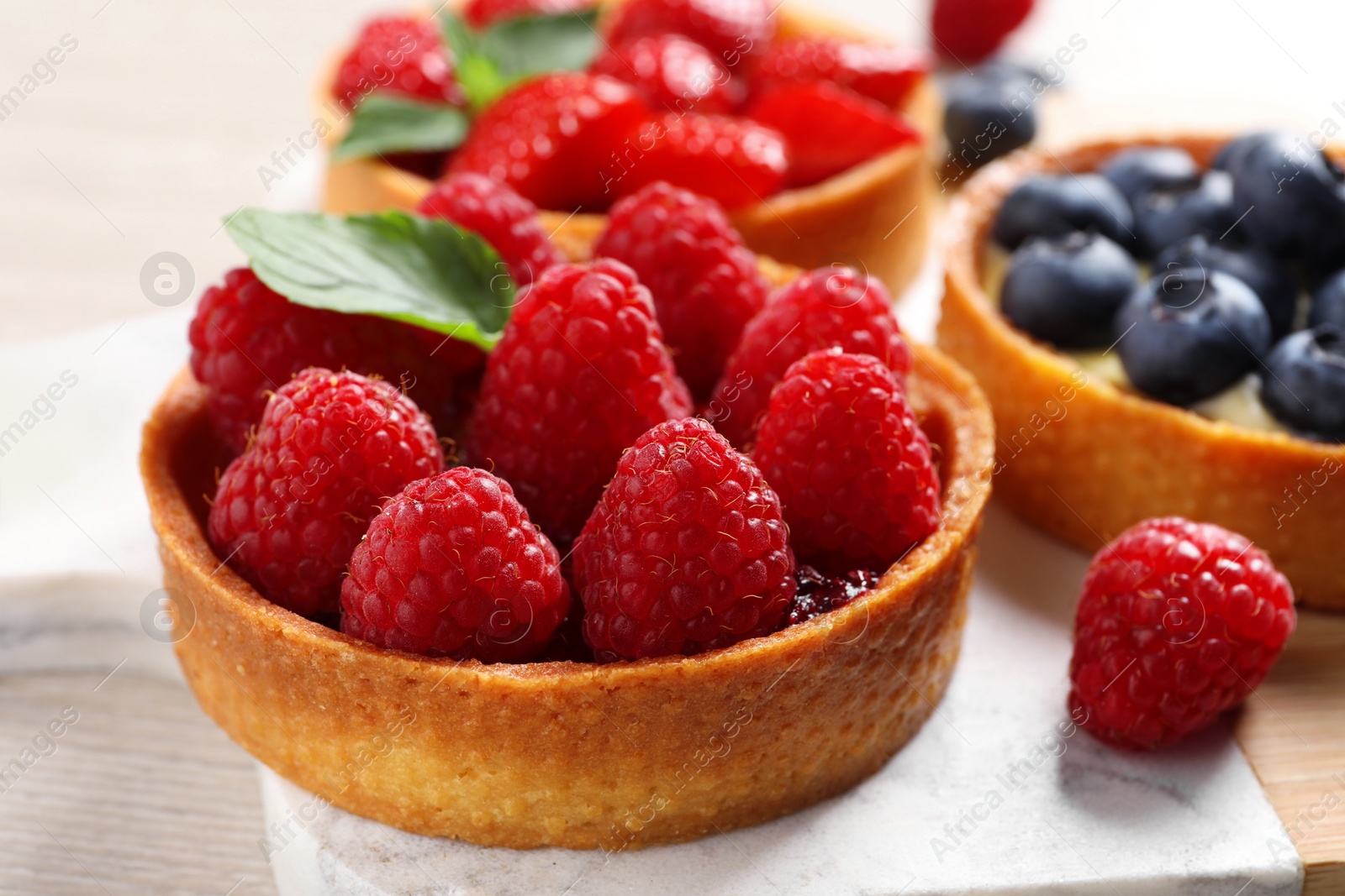 Photo of Tartlet with fresh raspberries on table, closeup. Delicious dessert