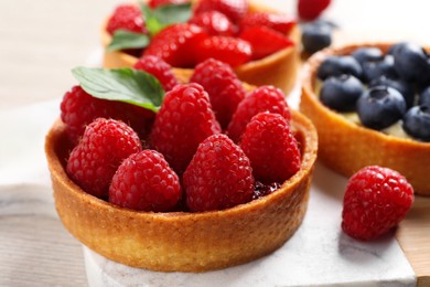 Photo of Tartlet with fresh raspberries on table, closeup. Delicious dessert