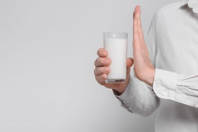 Man with glass of milk suffering from lactose intolerance on white background, closeup. Space for text