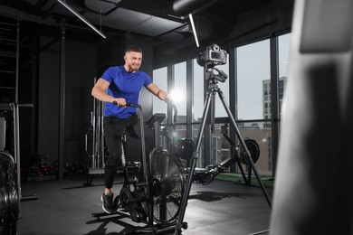Man recording workout on camera at gym. Online fitness trainer