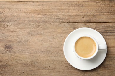 Photo of Aromatic coffee in cup on wooden table, top view. Space for text