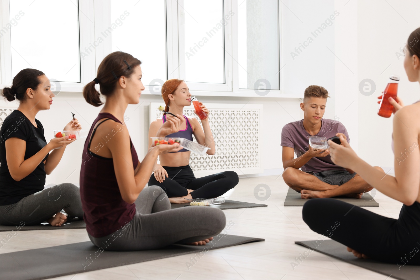 Photo of Group of people eating healthy food after yoga class indoors