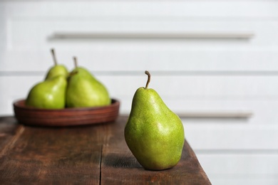 Ripe pear on wooden table against blurred background