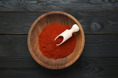 Photo of Bowl of aromatic paprika on black wooden table, top view
