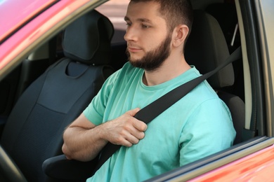 Photo of Man with fastened safety belt on driver's seat in car