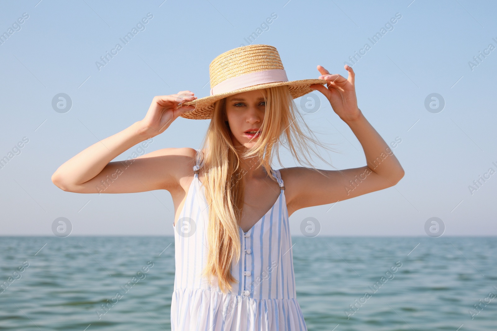 Photo of Beautiful young woman with straw hat near sea on sunny day in summer