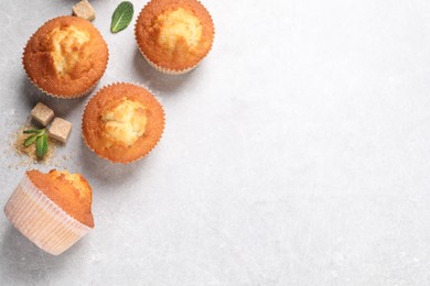 Photo of Delicious sweet muffins and brown sugar on light grey textured table, flat lay. Space for text