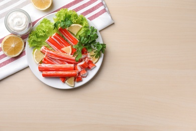 Photo of Delicious crab sticks served on wooden table, flat lay. Space for text