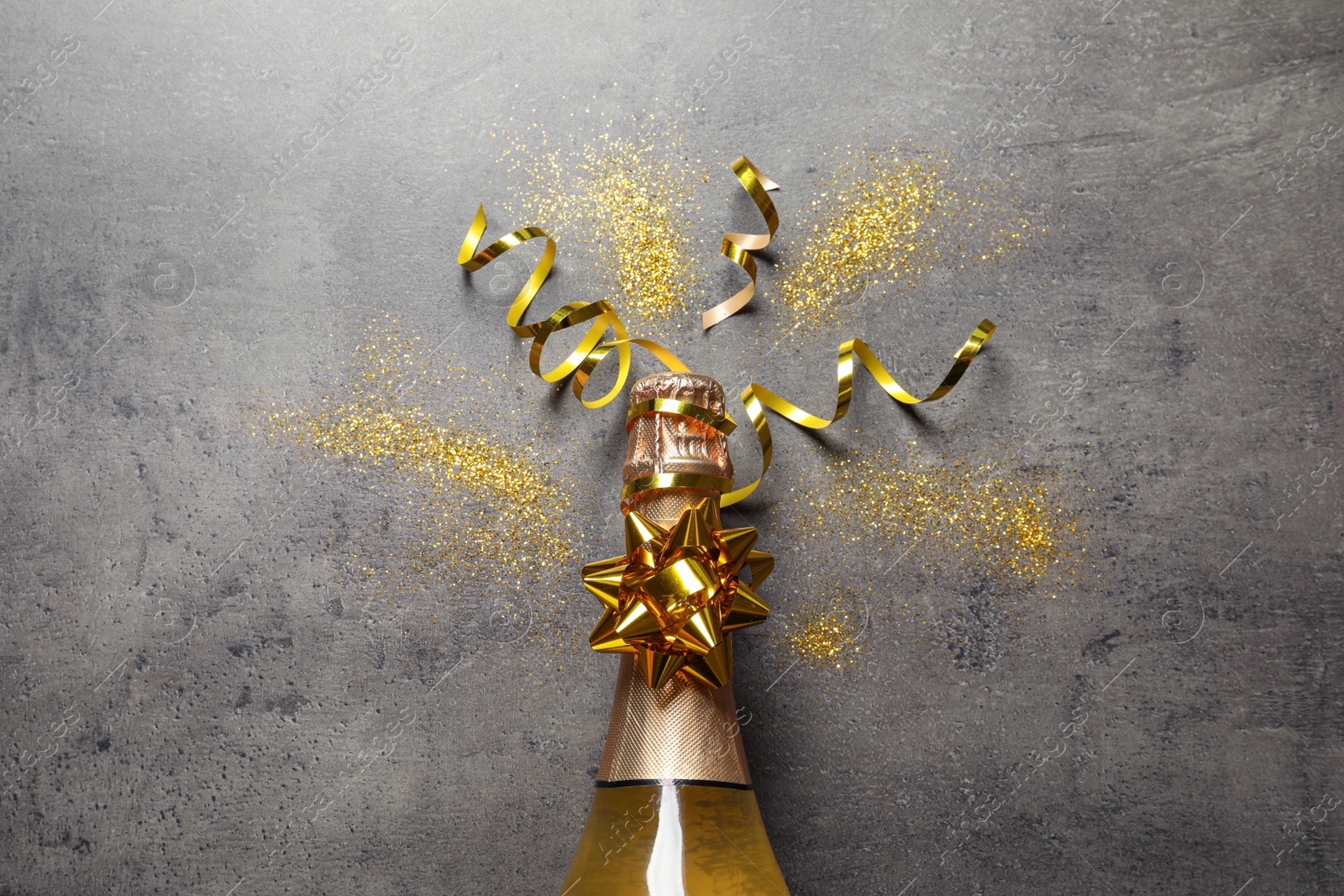 Photo of Flat lay composition with bottle of champagne for celebration on grey stone background