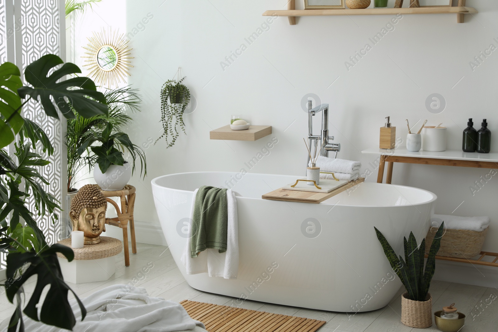 Photo of Stylish bathroom interior with modern tub, houseplants and beautiful decor. Home design