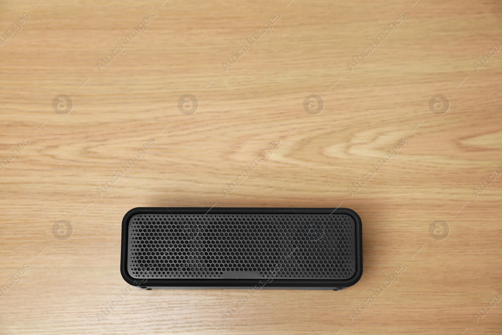 Photo of One portable bluetooth speaker on wooden table, top view with space for text. Audio equipment