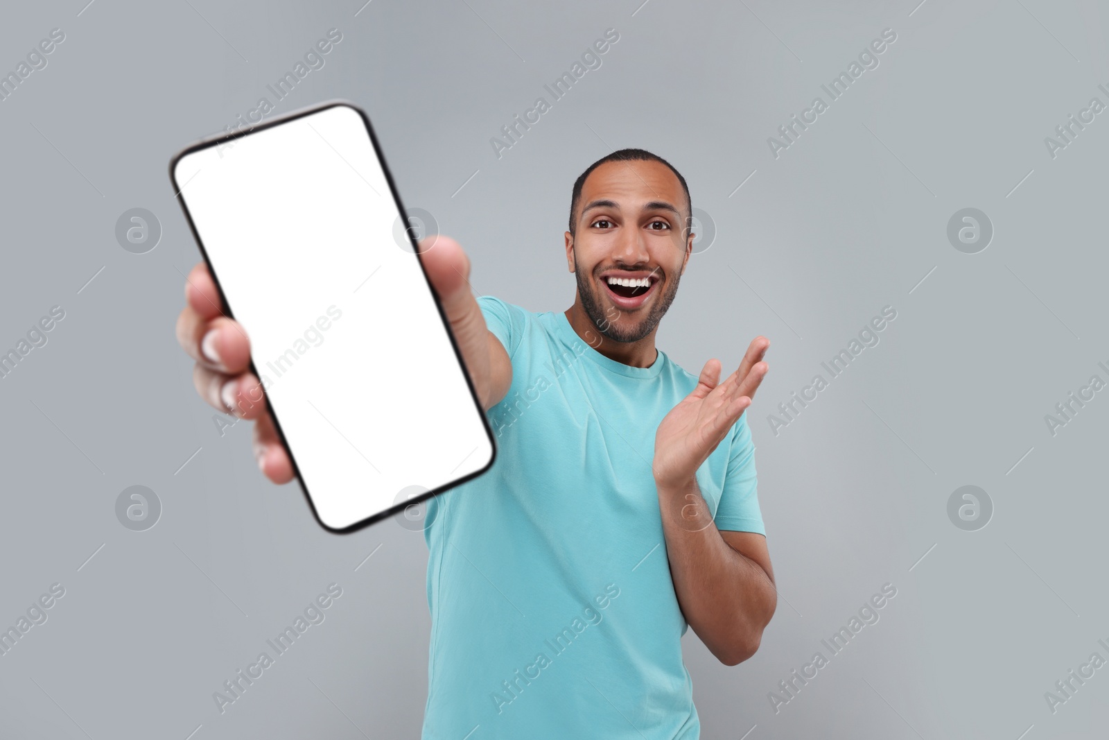 Photo of Surprised man showing smartphone in hand on light grey background