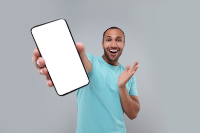 Surprised man showing smartphone in hand on light grey background