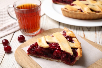 Photo of Slice of delicious fresh cherry pie on white wooden table, closeup