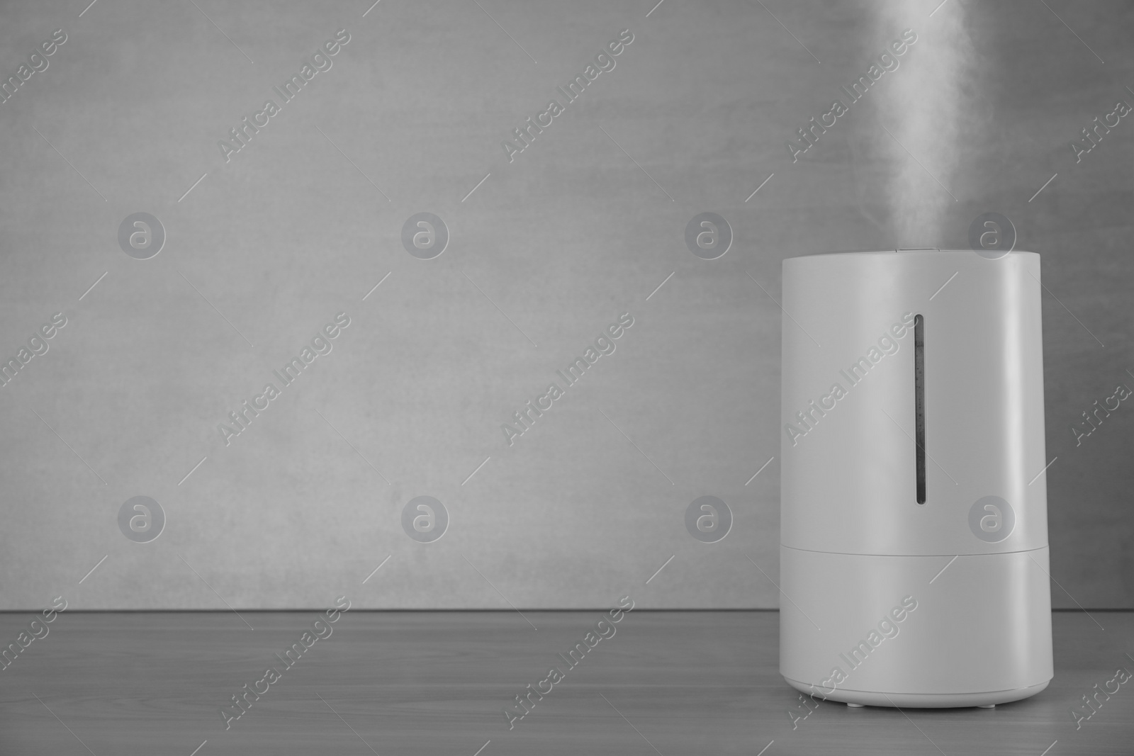 Photo of Modern air humidifier on table against grey background. Space for text