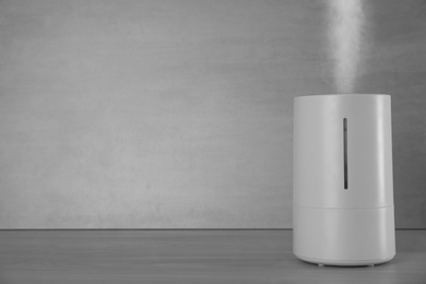 Modern air humidifier on table against grey background. Space for text