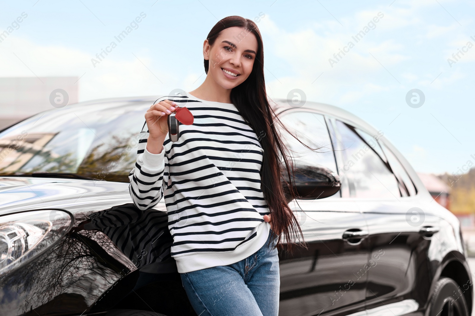 Photo of Woman holding car flip key near her vehicle outdoors