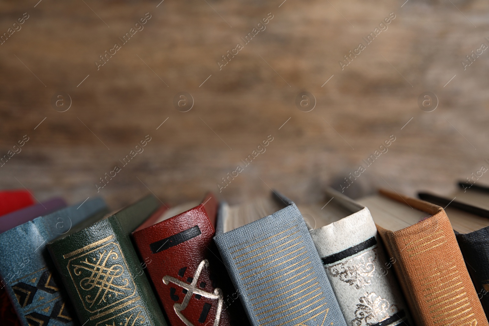 Photo of Stack of hardcover books on wooden background, closeup. Space for text