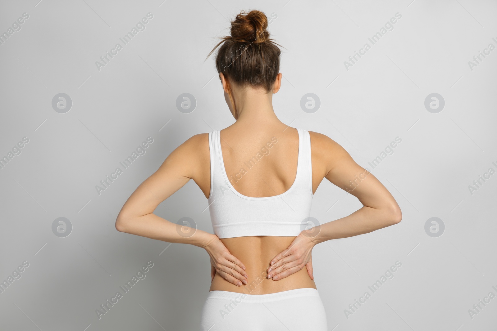 Photo of Woman suffering from pain in back on light grey background