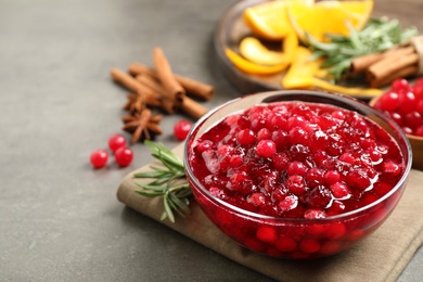 Fresh cranberry sauce served in glass bowl on grey table, space for text