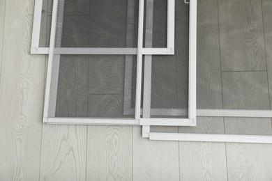 Photo of Set of window screens on wooden floor, flat lay