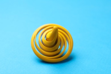 Photo of One yellow spinning top on light blue background, closeup