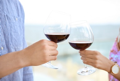 Photo of Young romantic couple with glasses of red wine outdoors
