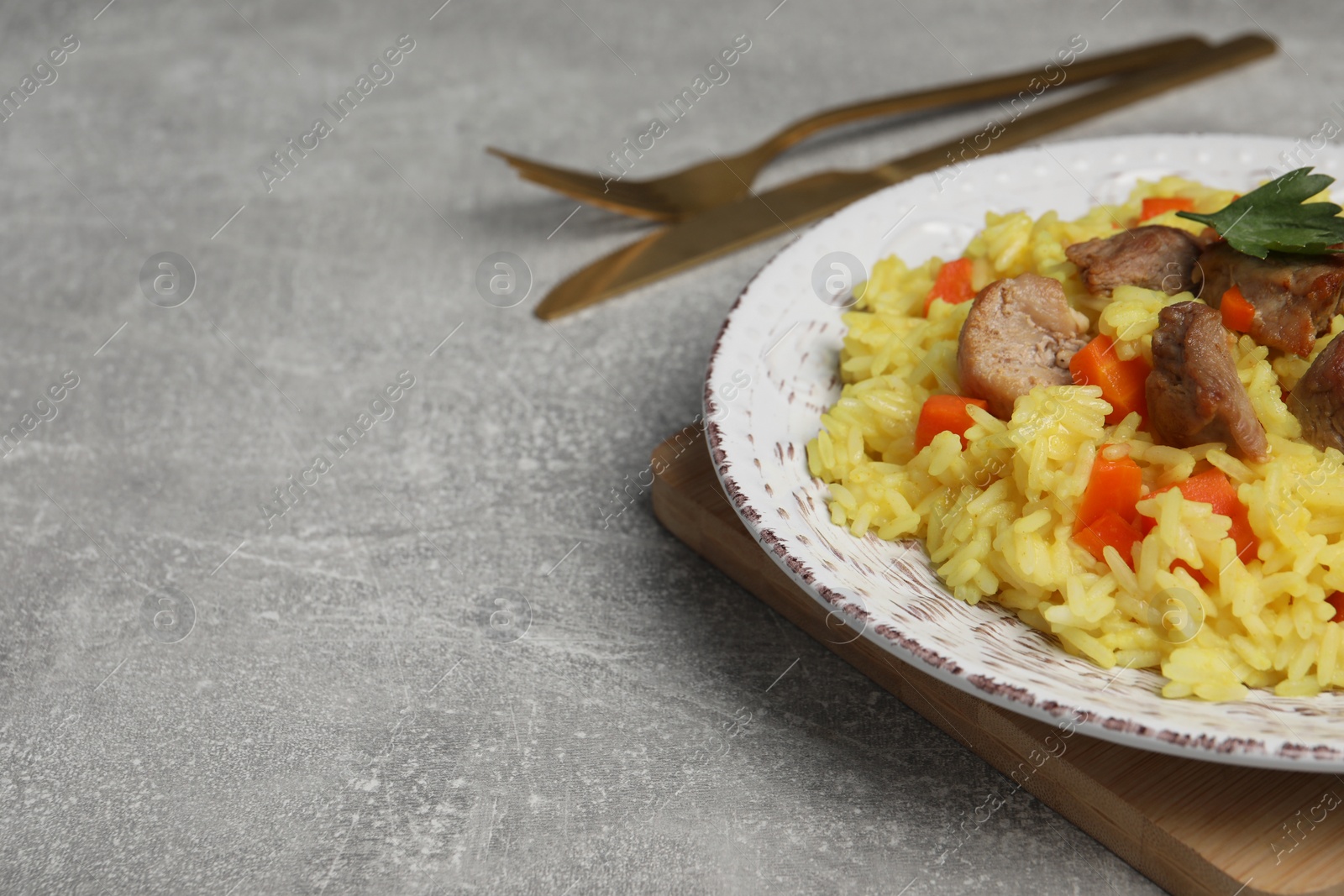 Photo of Delicious pilaf with meat served on light grey table, closeup. Space for text