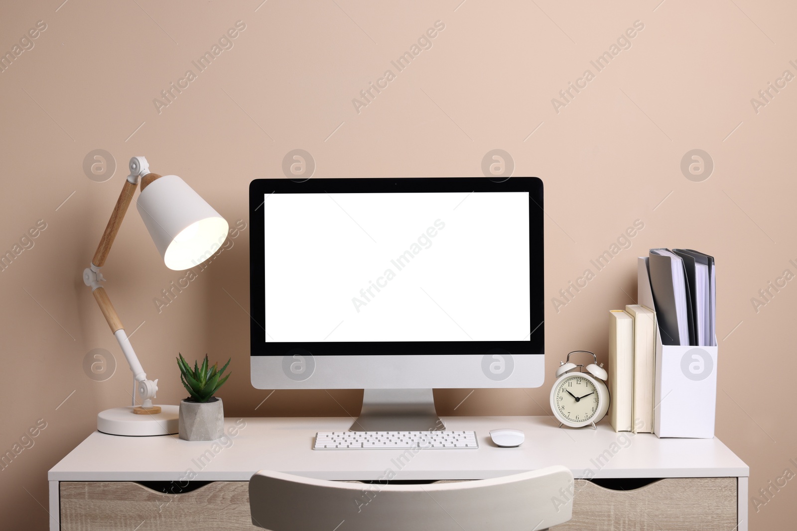 Photo of Cozy workspace with computer, lamp, houseplant and stationery on wooden desk