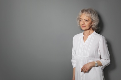 Portrait of mature woman on grey background. Space for text