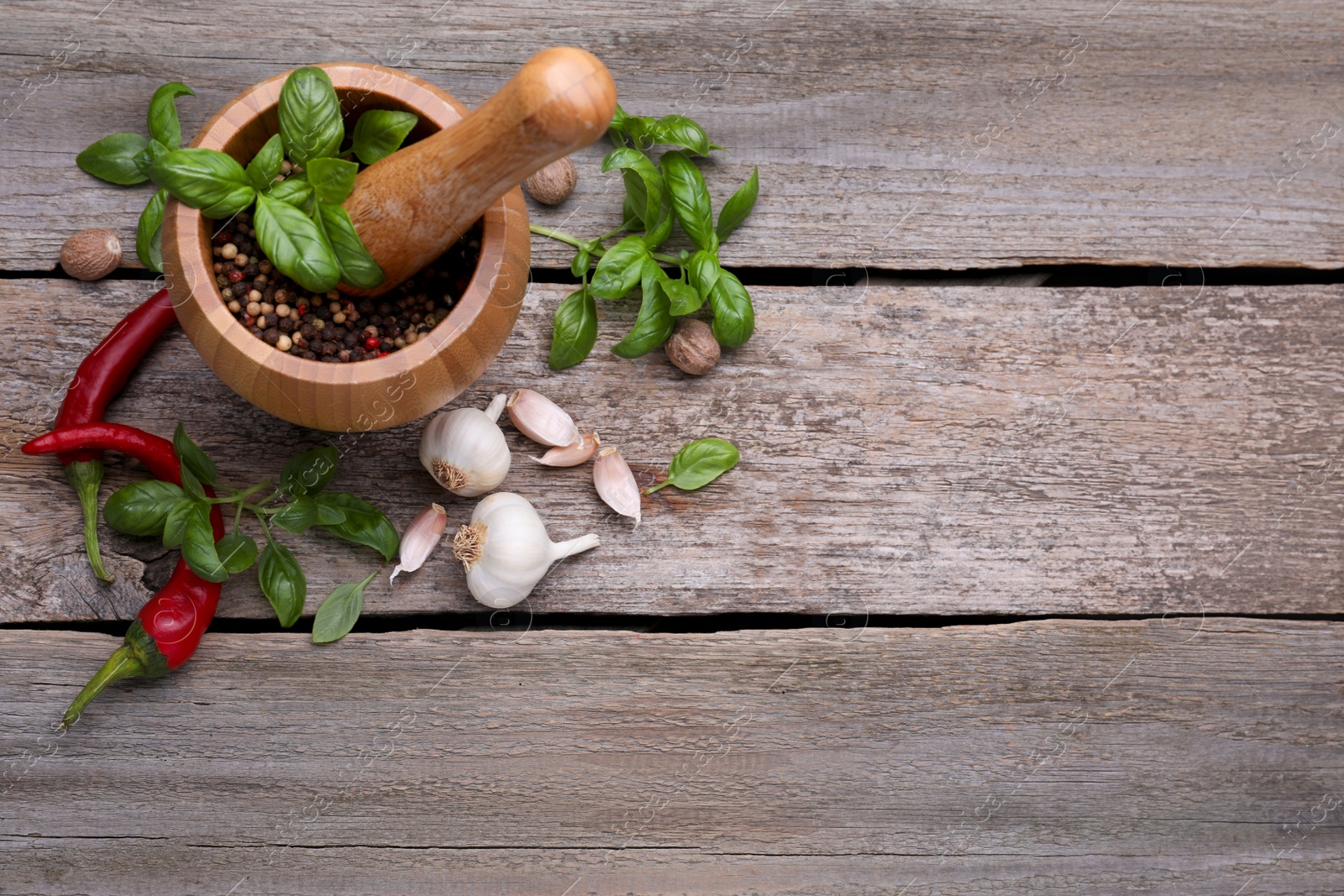 Photo of Mortar with pestle and different spices on wooden table, above view. Space for text