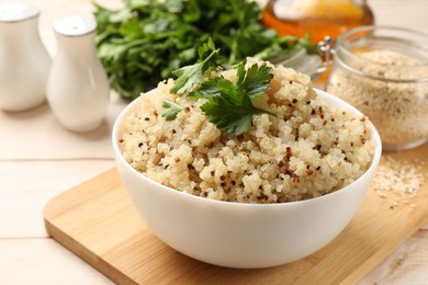 Photo of Tasty quinoa porridge with parsley in bowl on light table, closeup