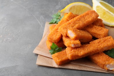 Photo of Fresh breaded fish fingers served on grey table, space for text